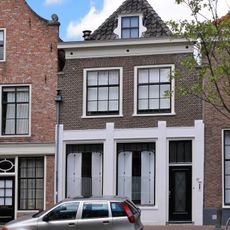 Pand met ingezwenkte gevel met lijst en in de verdieping schuiframen