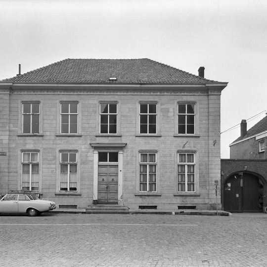 Deftig, gepleisterd herenhuis. Bewerkte kroonlijst, omlopend schilddak en stoep