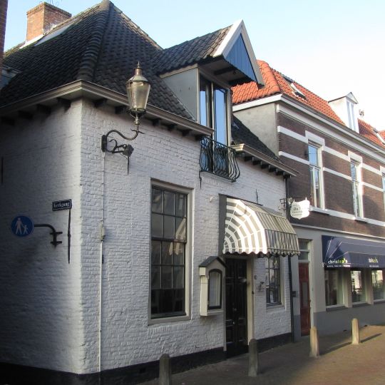 Laag gewit huis met hijsbalk. Bakstenen voor- en achtergevel