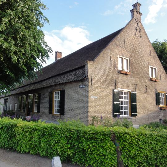 Boerderij van het noordbrabantse langgeveltype, in gele baksteen, onder zadeldak op lagere achtergevel, en met zijtopgevel waarin duivengaten, toppilaster
