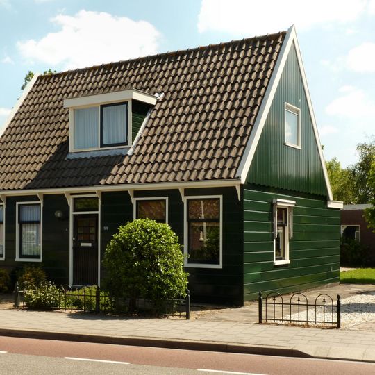 Houten huis met schilddak evenwijdig aan de straat. Inwendig een gesneden plafond