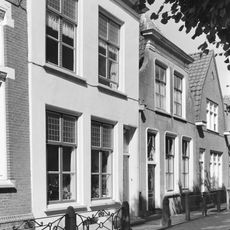 Gepleisterde lijstgevel, schuifvensters met brede middenstijl gedecoreerd met bladmotief. Het huis achter deze gevel vernieuwd