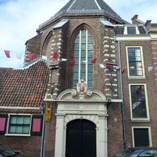 Ingangspoort van koor van Sint Janskerk met natuursteen versierd, door Haarlems wapen in cartouche bekroond