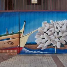 Mural que presenta la proa de una jábega junto a unas flores de biznaga de Málaga.