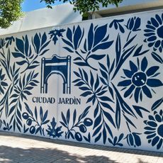 Mural inspirado en el distrito Ciudad Jardín tomando como punto de partida los motivos vegetales y florales del cercano jardín botánico La Concepción. Tiene una composición esquemática y geométrica que recuerda a los azulejos tradicionales andaluces.
