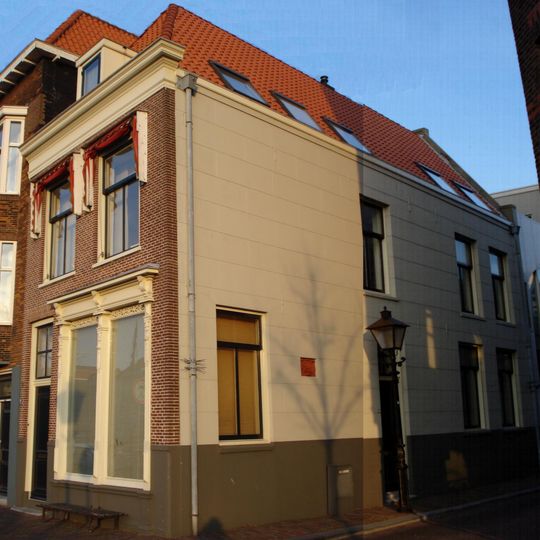 Pand met verdieping en pannen schilddak, dat aan de achterzijde aansluit tegen een puntgevel