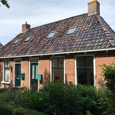 Breed landelijk pand met goot op klossen onder schilddak met twee hoekschoorstenen (vormt een geheel met nr. 30)