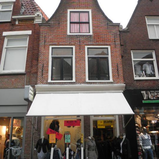 Smal pand waarvan de gevel door een ingezwenkte halstop wordt beëindigd met rococo kuifstuk