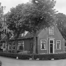 Kleine oorspronkelijke boerderij met puntgevel, waarin vlechtingen en ramen met goede roedenverdeling