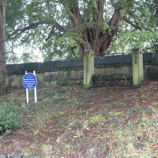 Parish stocks in front of east wall of St Wilfred's Churchyard