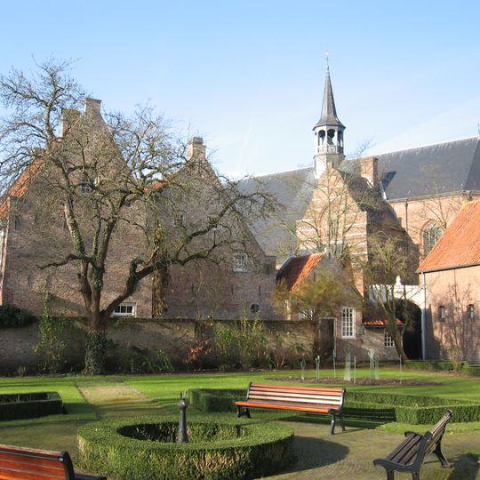 Diep achter een poort gelegen groot huis onder dwars zadeldak tussen zijtrapgevels