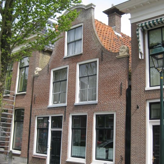 Pand onder zadeldak tegen klokgevel met aanzetkrullen en deklijst