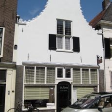 Pand met gepleisterde klokgevel met randen bloemen, natuursteen