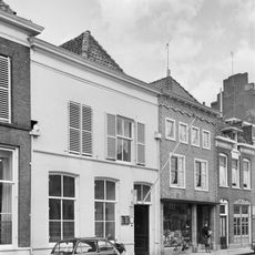 Pand met verdieping en schilddak, dat aan de achterzijde aansluit tegen een gepleisterde puntgevel. Voorgevel met kroonlijst