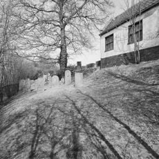 Begraafplaats omgeven door een haag van laurier, gelegen op een langgerekt perceel op de dijk van een wiel buiten de bebouwde kom van Leerdam, oostelijk van Oosterwijk