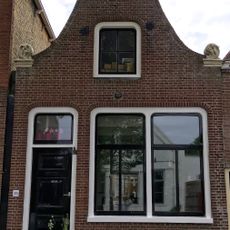 Pand met zeer eenvoudige herbouwde klokgevel met aanzetkrullen