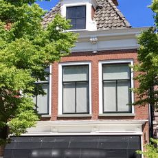 Pand onder zadeldak met voorschild met versierde dakkapel en schoorsteen met bord