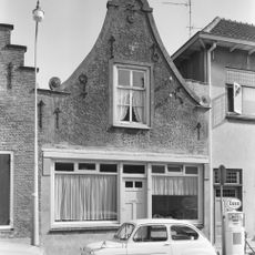 Huis met gecementeerde klokgevel met aanzetvoluten