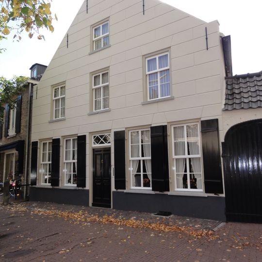 Huis met eenvoudige gebosseerd gepleisterde tuitgevel