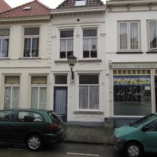 Huis met eenvoudige geelgepleisterde lijstgevel en schilddak