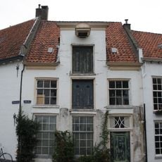 Gepleisterd woonhuis met rechte kroonlijst, in midden verhoogd met hijsbalk