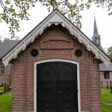 Baarhuis en toegangshek op negentiende-eeuwse kerkhof, rondom de van oorsprong veertiende-eeuwse kerk , die tegenwoordig wordt gebruikt door de Hervormde Gemeente