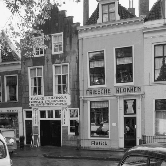 Pand onder zadeldak tegen gepleisterde trapgevel met toppilasters