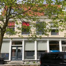 Breed pand onder dwarsdak met gepleisterde gevel en drie grote gevelstenen