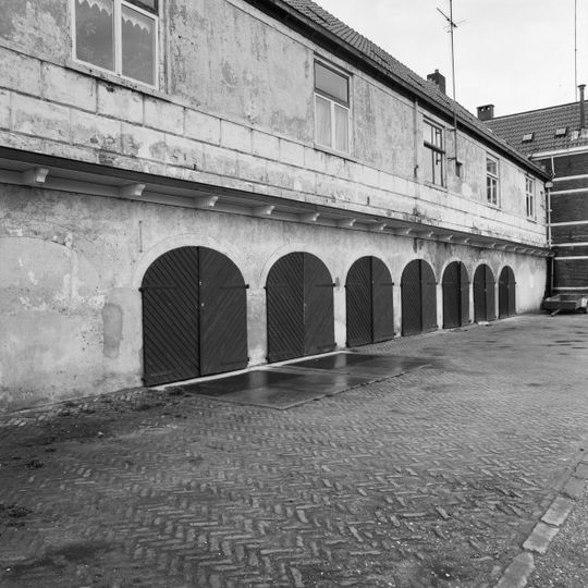 Blok van negen kleine gepleisterde woonhuizen in neoklassicistische stijl boven 17e-eeuwse opslagkelders