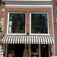 Lage tussenbouw met recht geprofileerde kroonlijst en twee negenruitsvensters