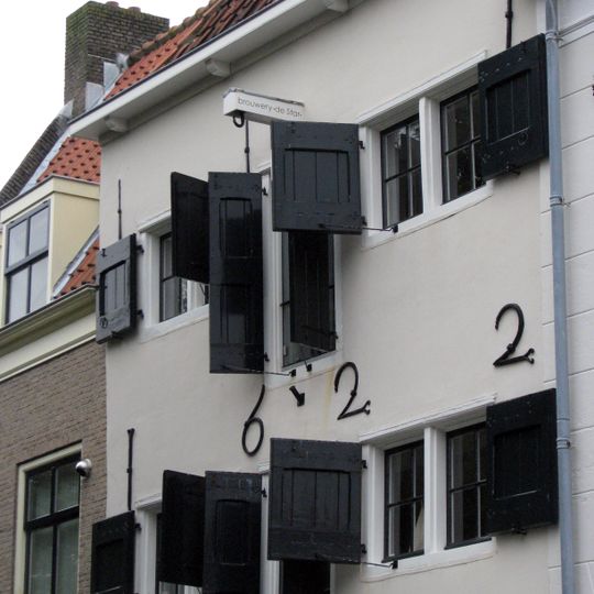 Pakhuis in lichte kleur gepleisterd van drie bouwlagen onder een schilddak