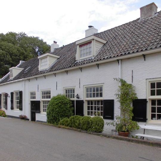 Gepleisterd laag huis, ramen met kleine roeden en halve luiken, zadeldak