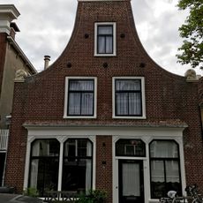 Pand onder zadeldak klokgevel met aanzetkrullen