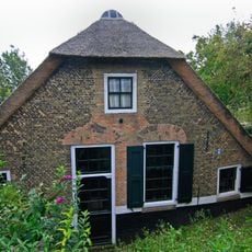 Boerderij onder rieten wolfdak. In de voorgevel vlechtingen en ontlastingsbogen