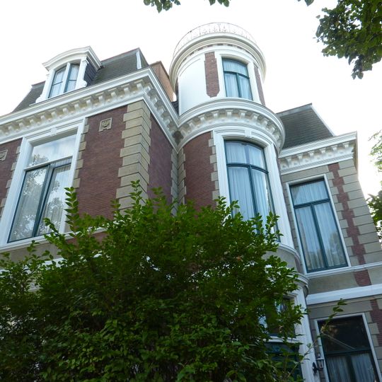 Vrijstaande villa in late eclectische stijl op L-vormige plattegrond met ijzeren tuinhek