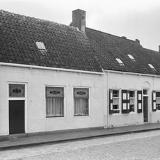 Dwarshuis met gepleisterde gevel aan het plein