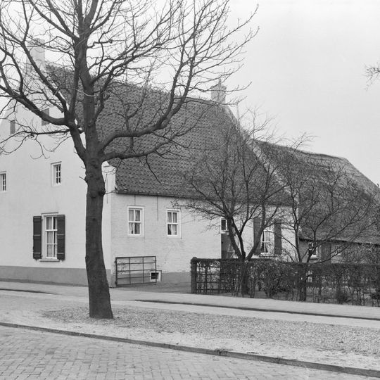 Boerderij met witgepleisterde gevel, zesdelige schuiframen en groene luiken