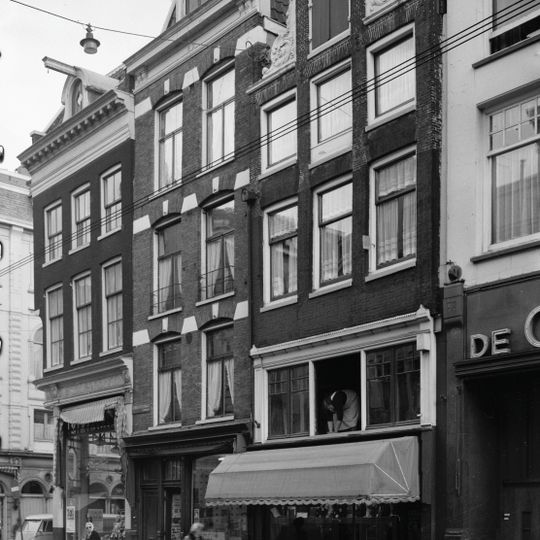 Hoekhuis met voorgevel onder rechte lijst met dakkapel afgeronde pui waarboven nis op de hoek