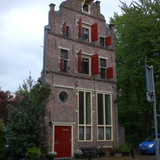 Huis in jaarankers gedateerd 1612, met in- en uitgezwenkte topgevel bekroond door vijf pilasters, die gedekt zijn door geprofileerde natuurstenen platen.