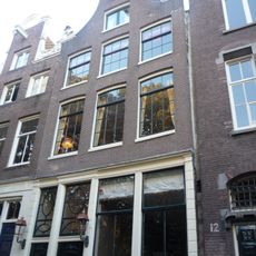 Pand met goed bewaarde ingezwenkte halsgevel met gesneden pui, dito deuren en goede roedenverdeling op de verdiepingen