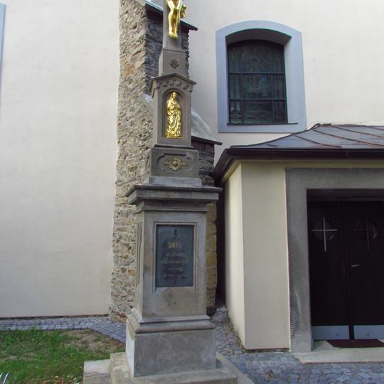 Tmavý kříž u kostela Nanebevzetí Panny Marie v Rouchovanech