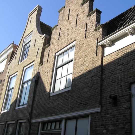 Aansluitend bij Poststraat 1 een aanbouw met lijstgevel en vervolgens een aanbouw met langsgevel aan de straat en ten slotte een trapgevel met geprofileerde dekstukken, puibalk.
