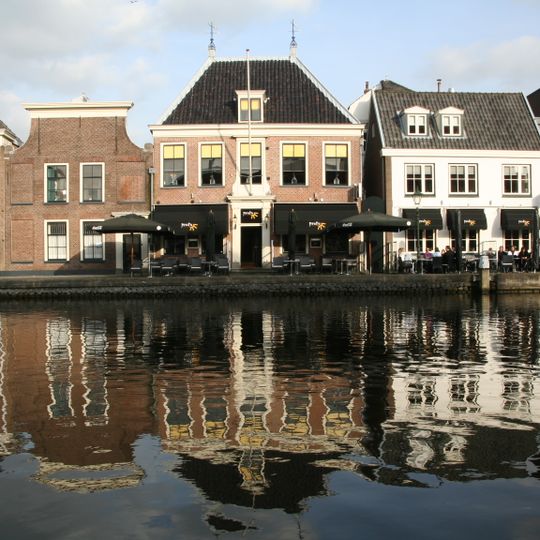 Herenhuis met verdieping en hoog, pannen schilddak, waarop hoekschoorstenen. Dakkapel. Houten middenpartij, waarin deuromlijsting met gecanneleerde pilasters en hoofdgestel en palmetkapitelen.