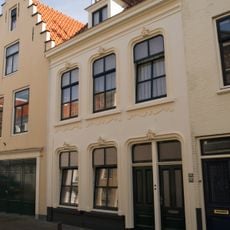 Huis gepleisterde lijstgevel. Vensters met afgeronde hoeken. Dakkapel. Dubbele voordeur