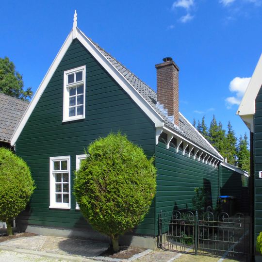 Houten huis met gerabatte wanden met zolderverdieping onder zadeldak met puntgevel met makelaar