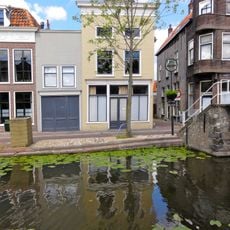 Hoekpand Lange Dwarsstraat met afgewolfd zadeldak. Gepleisterde lijstgevel. Mezzanino